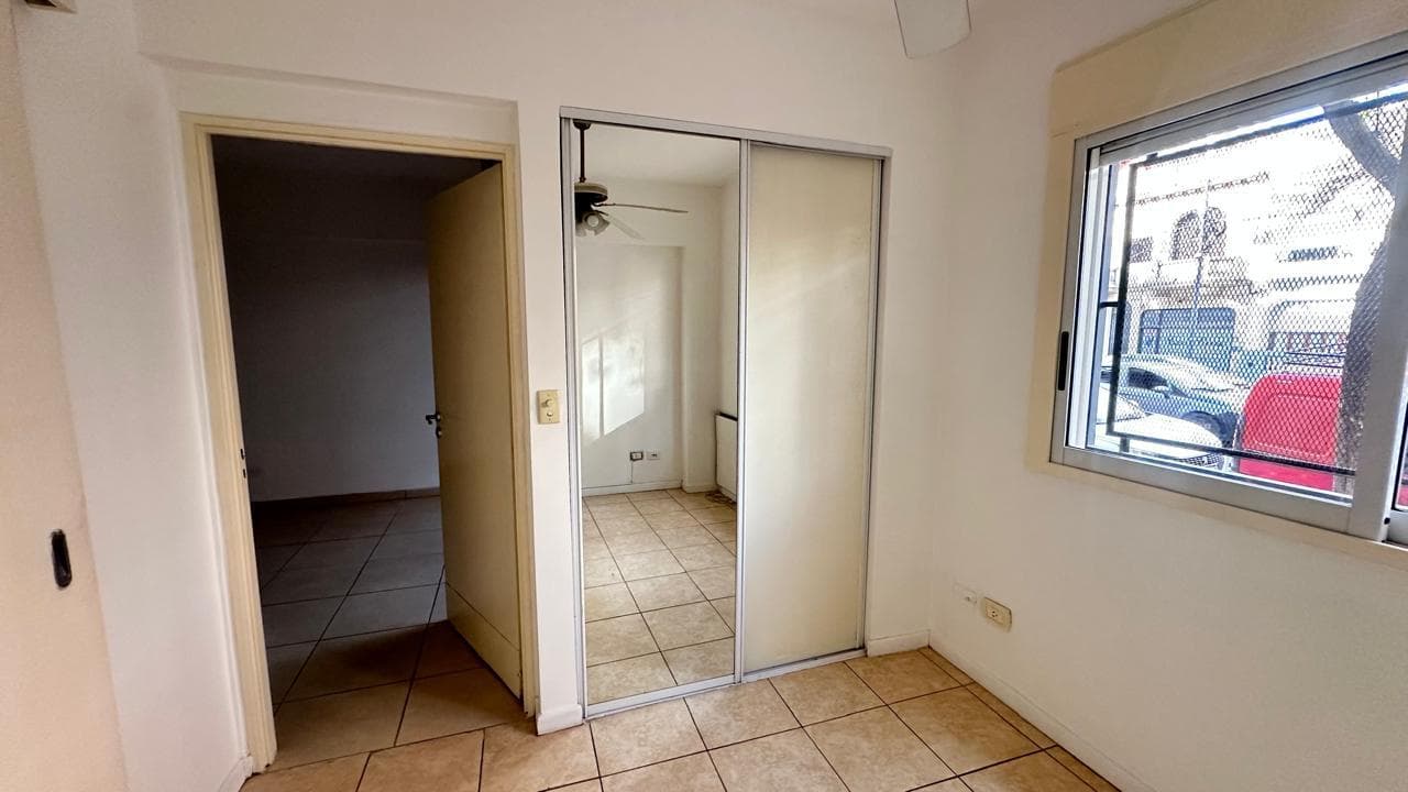 Dormitorio con ventana, placard con puertas espejadas y ventilador de techo.
