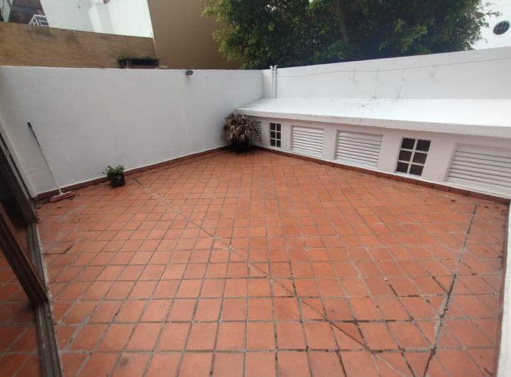 Patio exterior amplio con baldosas de terracota y paredes blancas.