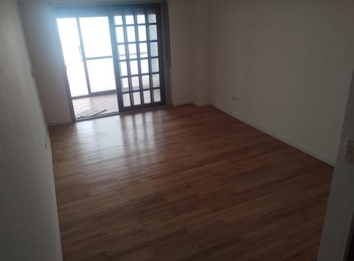 Dormitorio vacío con piso de madera y puerta corrediza al patio.