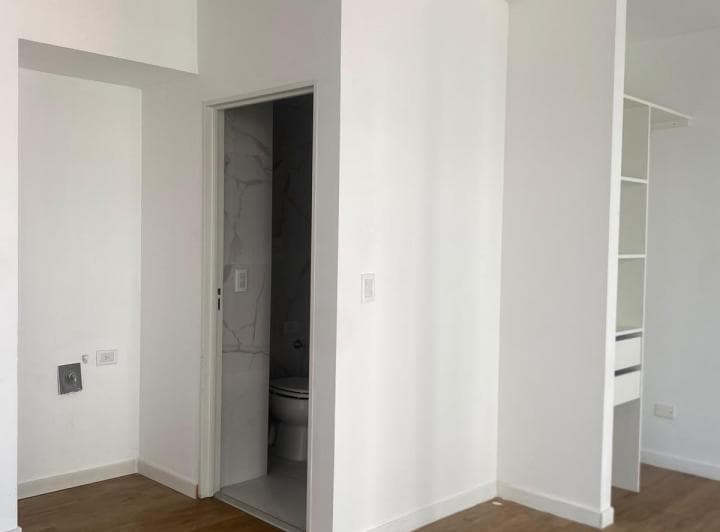 Pasillo de distribución con puerta al baño y estantería.