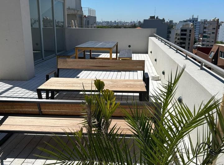 Terraza de edificio con mesas y bancos de madera.