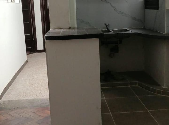 Cocina con barra, bacha y vista hacia un pasillo.