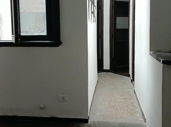 Pasillo con paredes blancas y puertas de madera oscura.