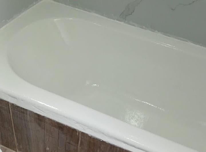 Bañera blanca con revestimiento de madera y azulejos blancos.