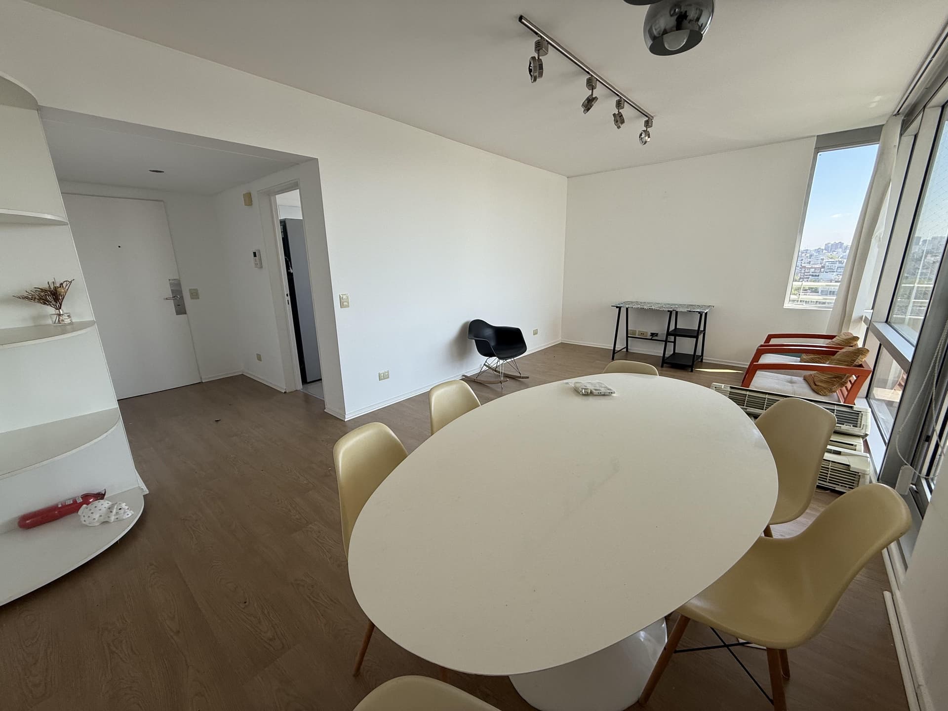 Living comedor con mesa, sillas, vista exterior y estantería blanca.