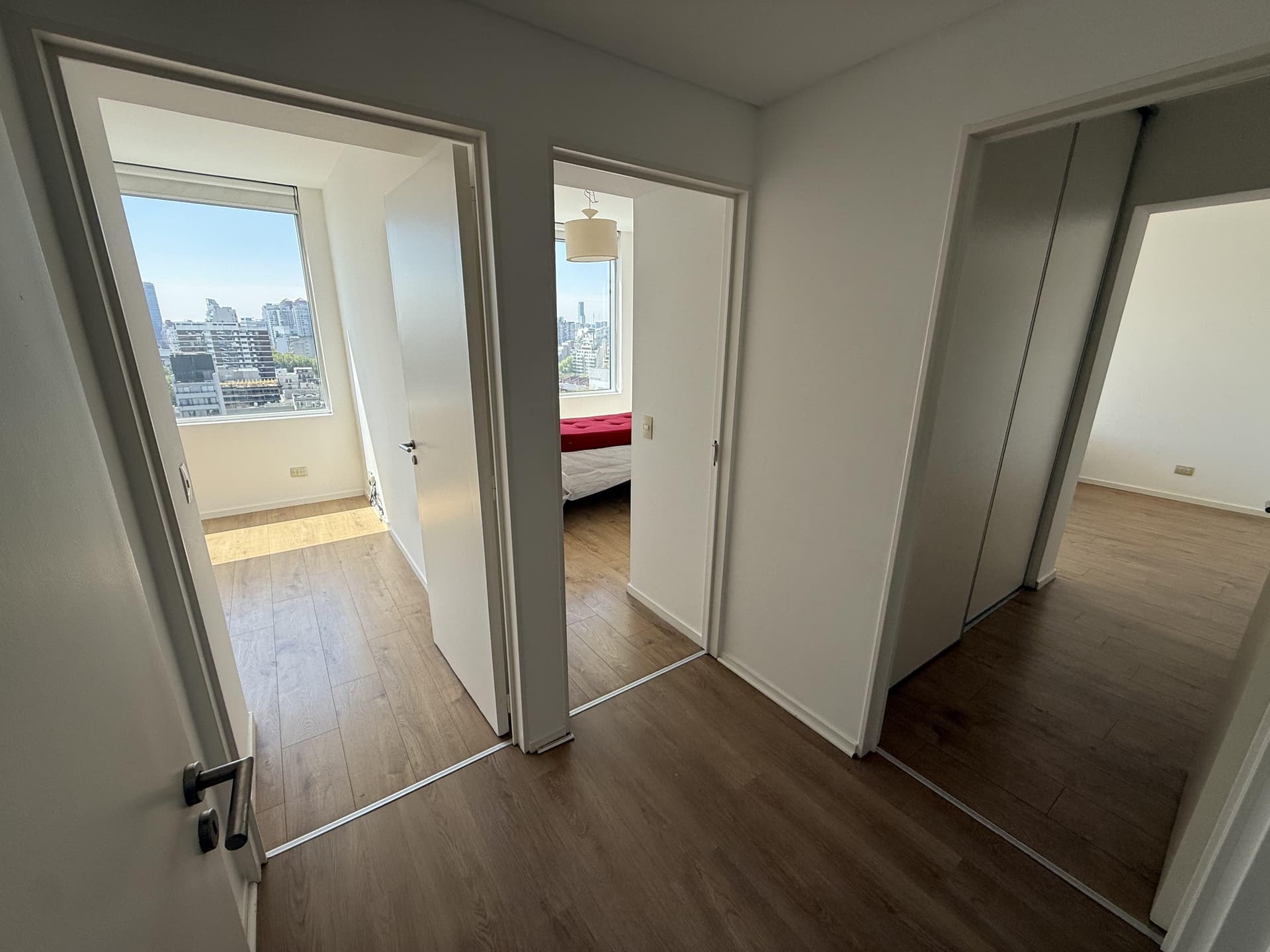 Pasillo de distribución con puertas de habitaciones y luz solar.