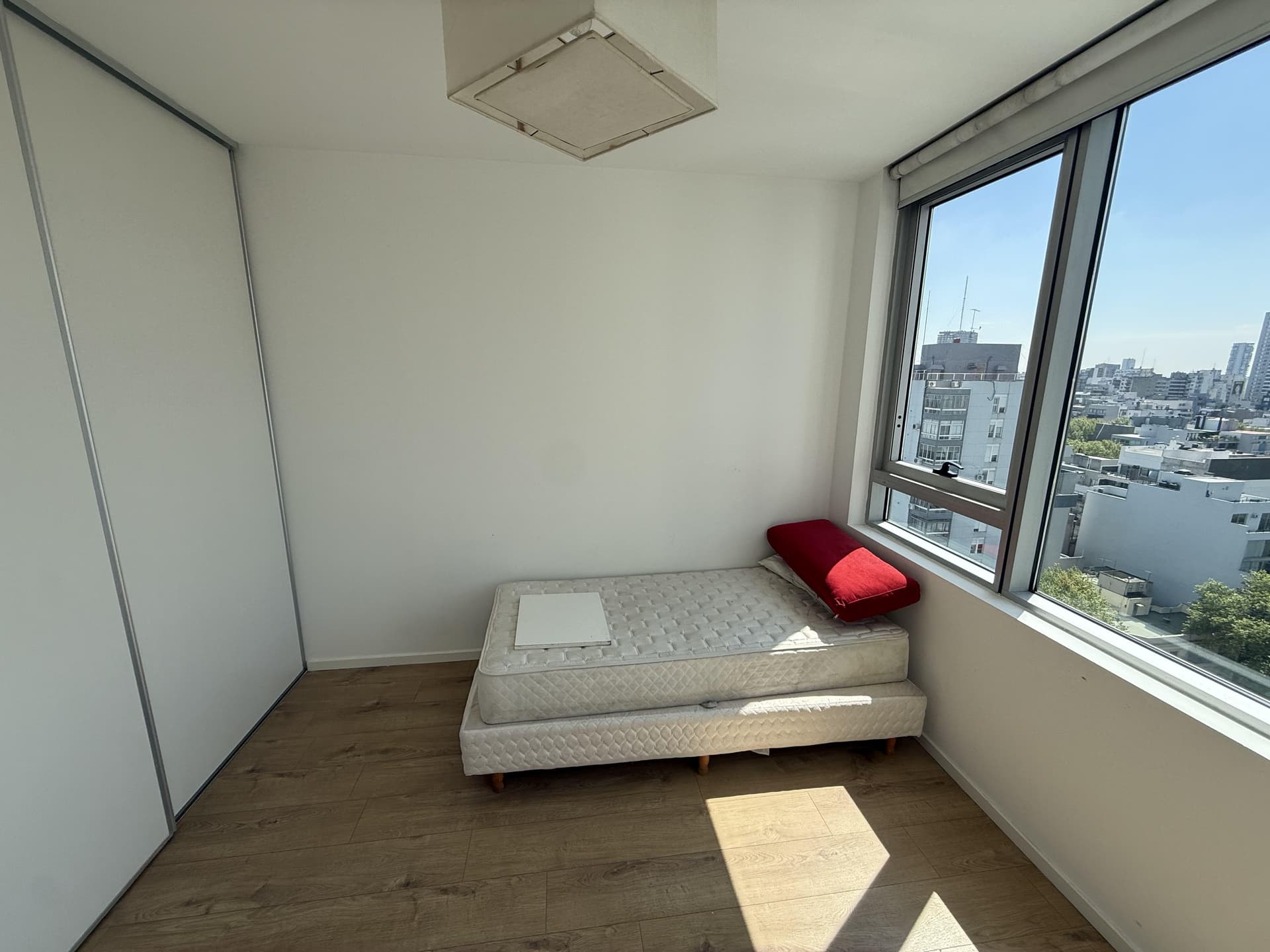 Dormitorio con cama individual, placard blanco y ventana con vista exterior.