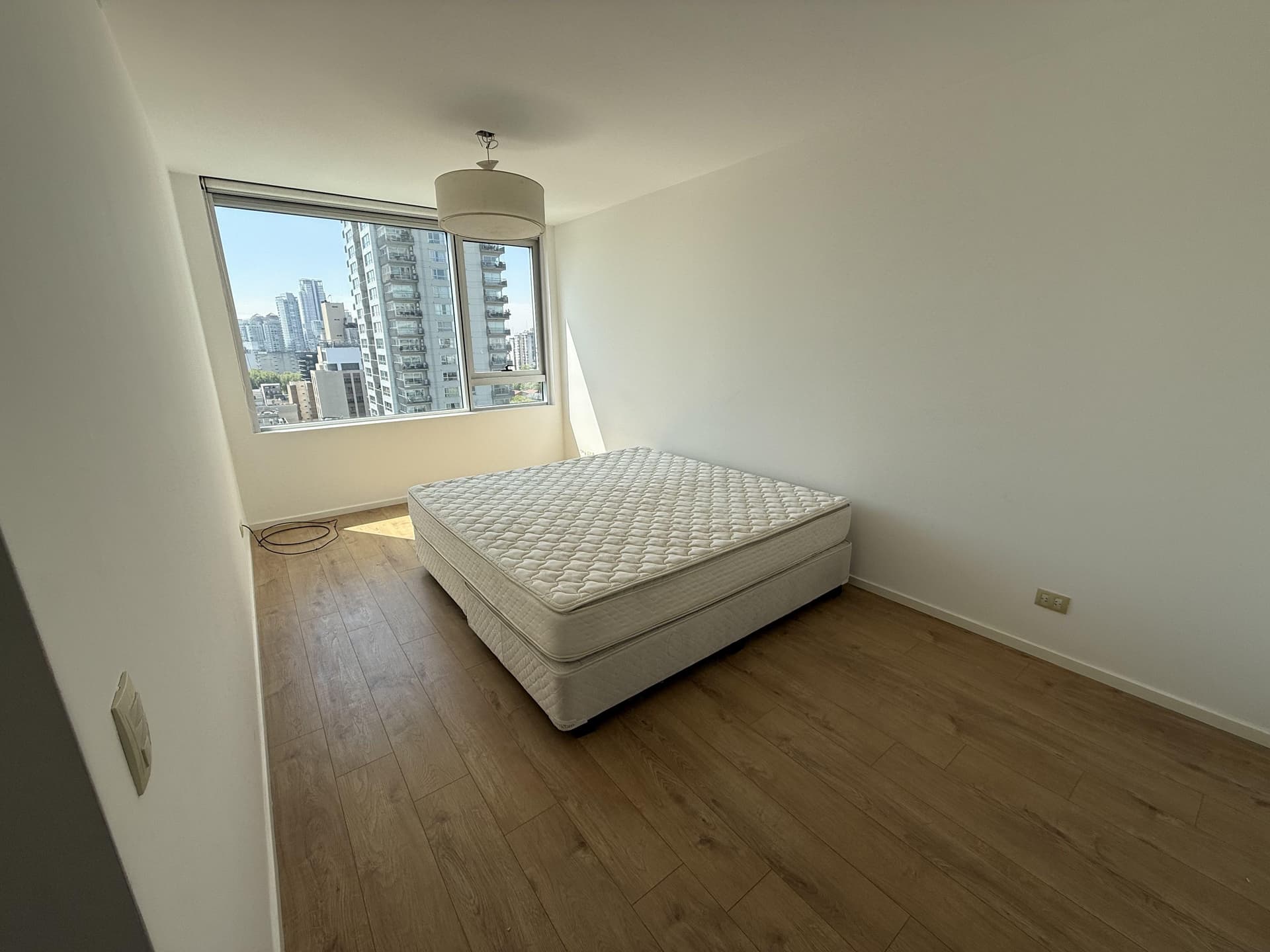 Dormitorio principal con cama doble y ventanal con vista a la ciudad.