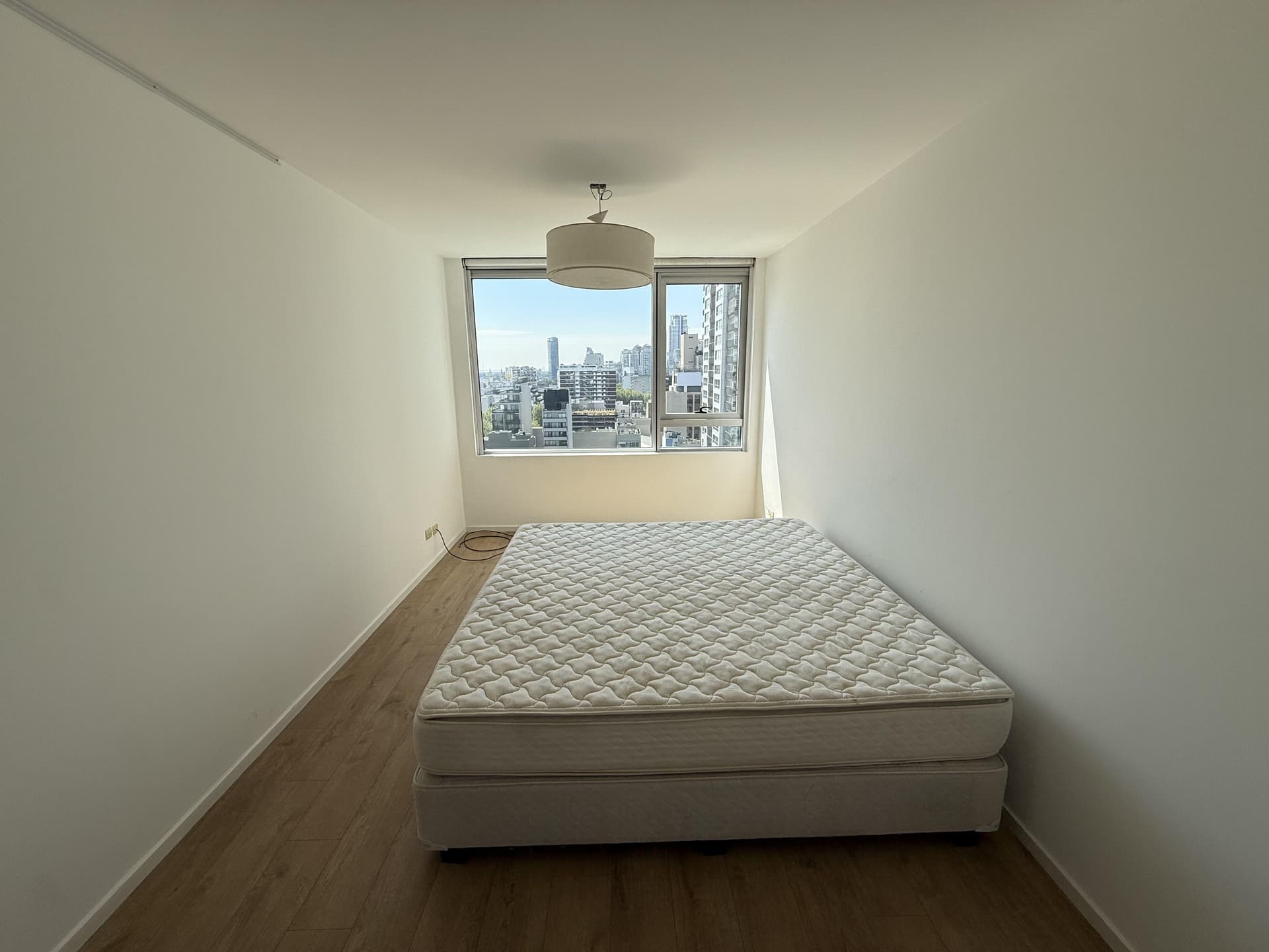 Dormitorio principal con cama doble y gran ventana con vista exterior.