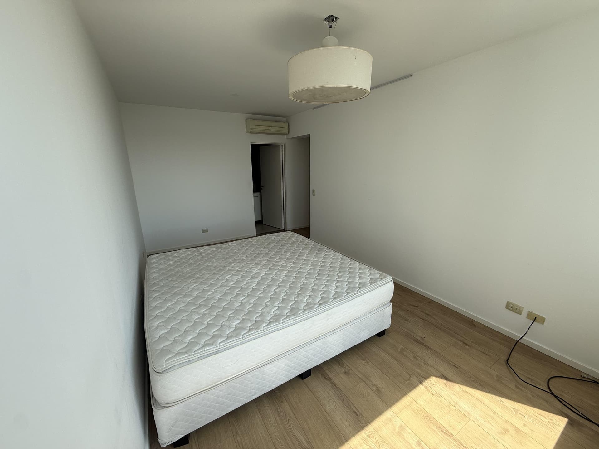 Dormitorio principal con cama doble y aire acondicionado en la pared.