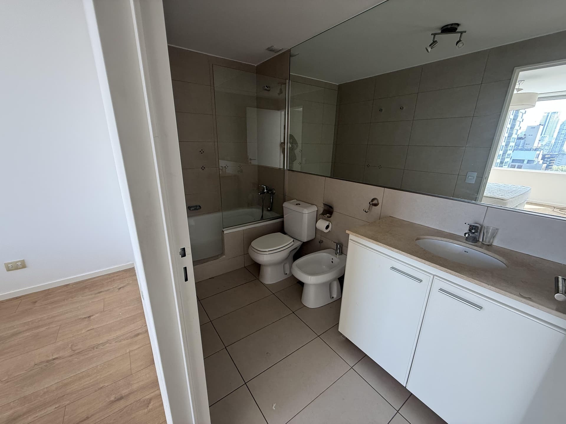 Baño completo con bañera, inodoro, bidet y vanitory con espejo.