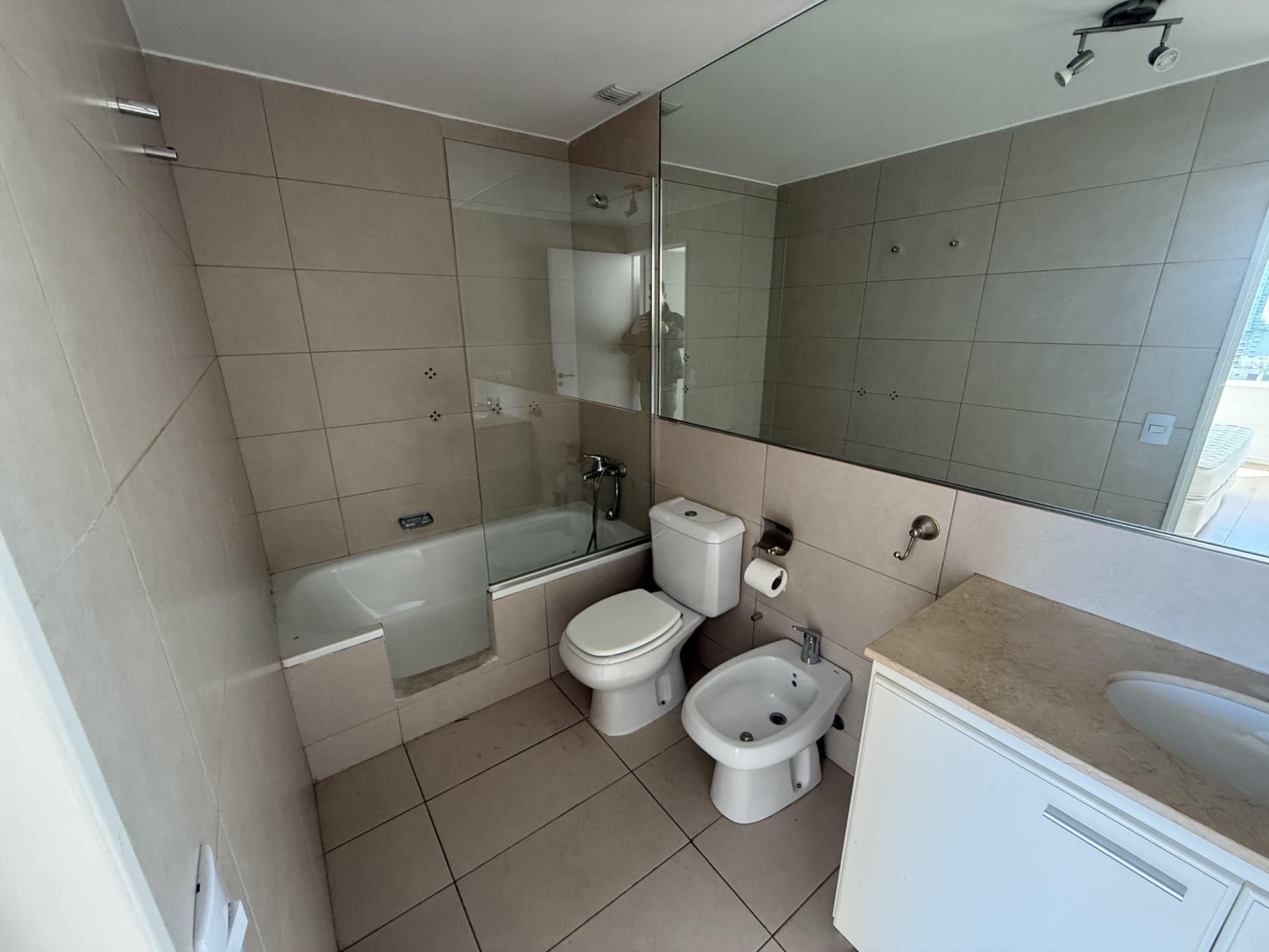 Baño completo con bañera con mampara de vidrio, inodoro y bidet.
