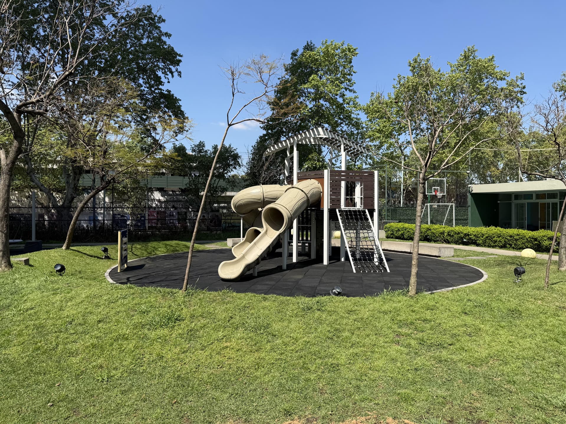 Área de juegos infantiles con toboganes y trepador en zona común.