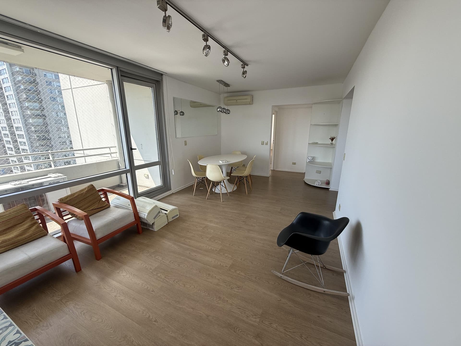 Living con mesa de comedor, sillones, balcón y espejo en la pared.