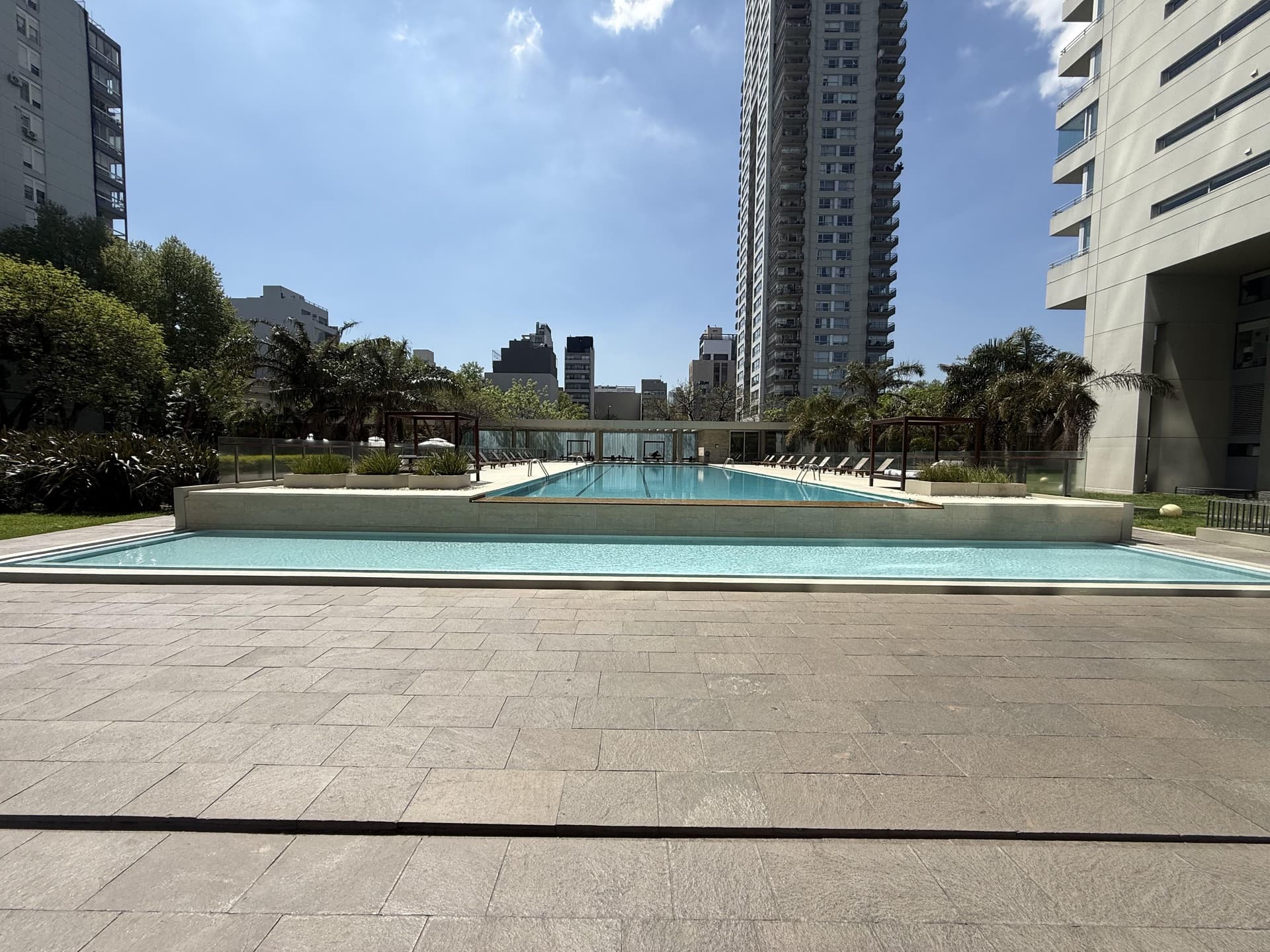Piscina larga al aire libre con edificios altos alrededor.