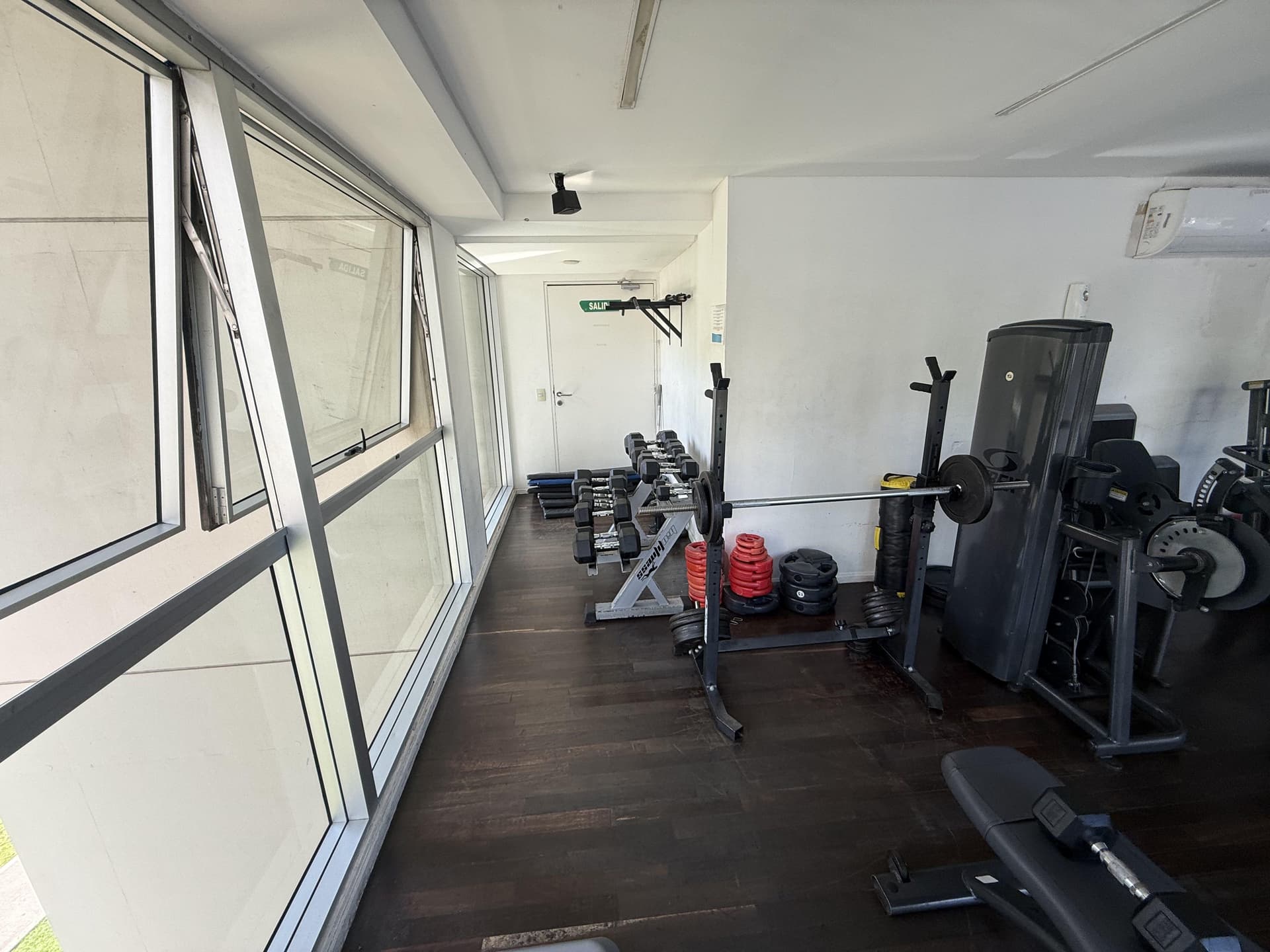 Gimnasio con pesas, mancuernas y aparatos de entrenamiento.