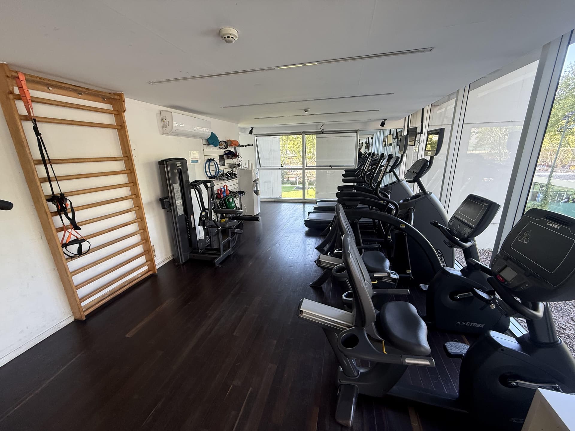Gimnasio con varios aparatos de entrenamiento y una espaldera.