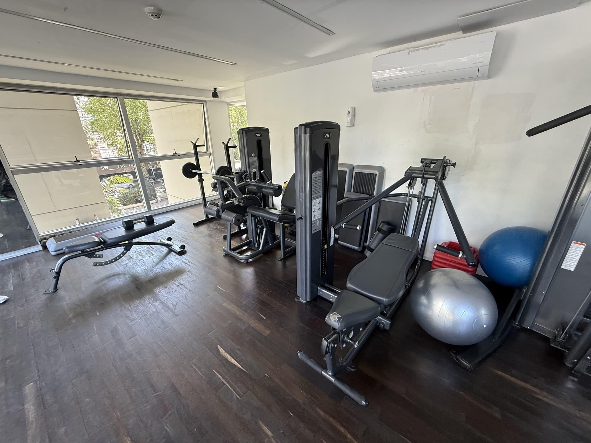Gimnasio con máquinas de musculación, pesas y pelotas de ejercicio.