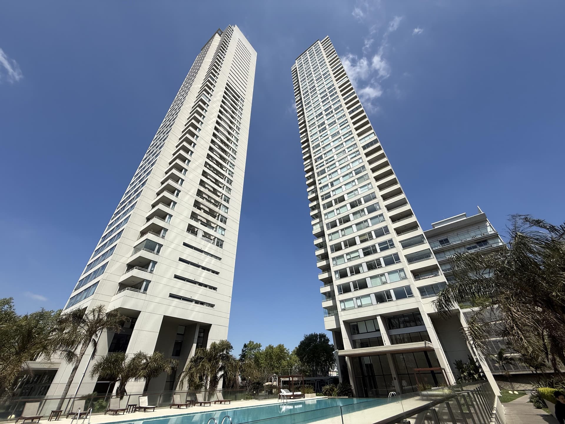 Dos edificios altos de arquitectura moderna bajo un cielo azul.