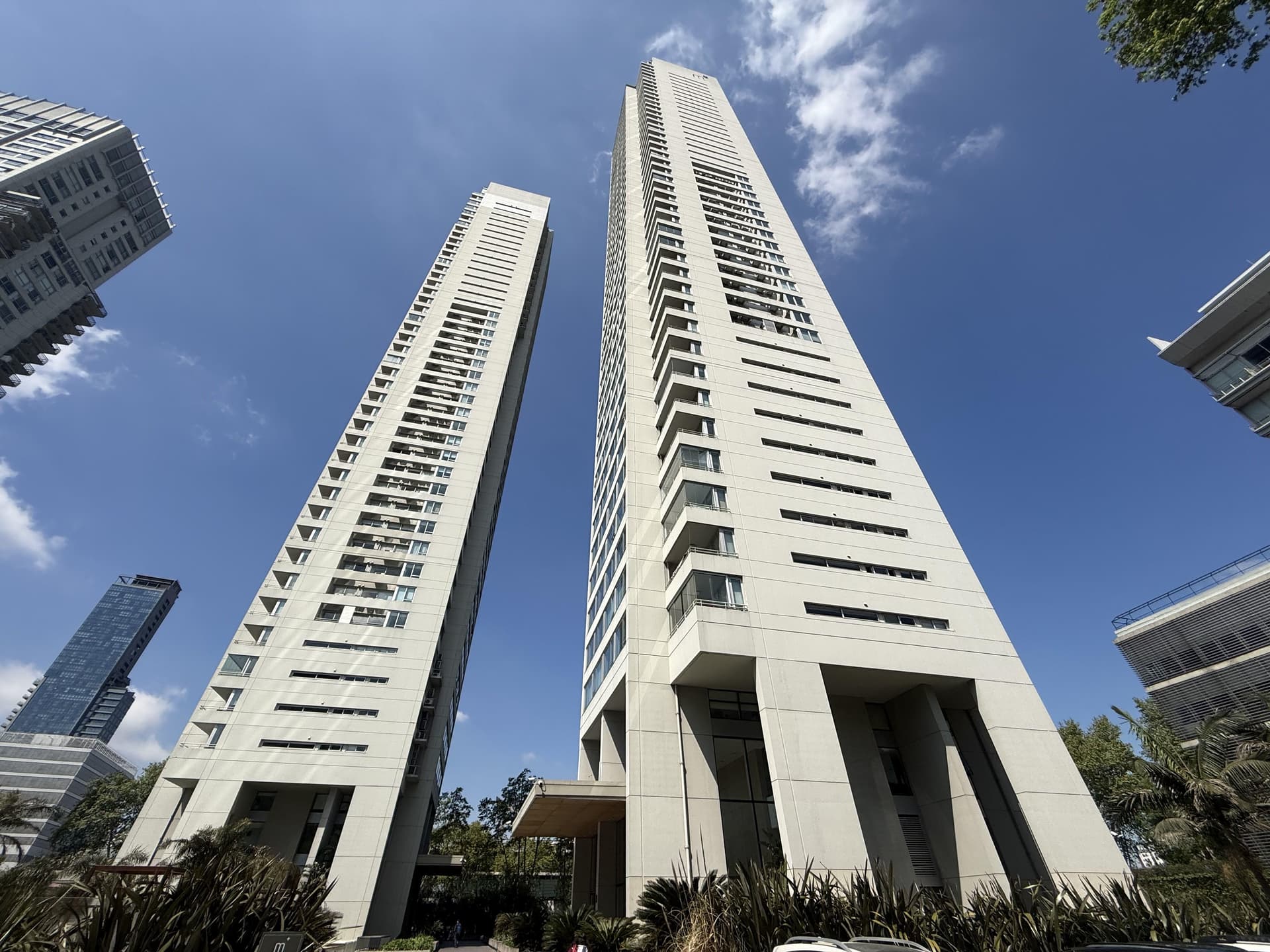 Fachada de dos edificios altos y modernos con palmeras.