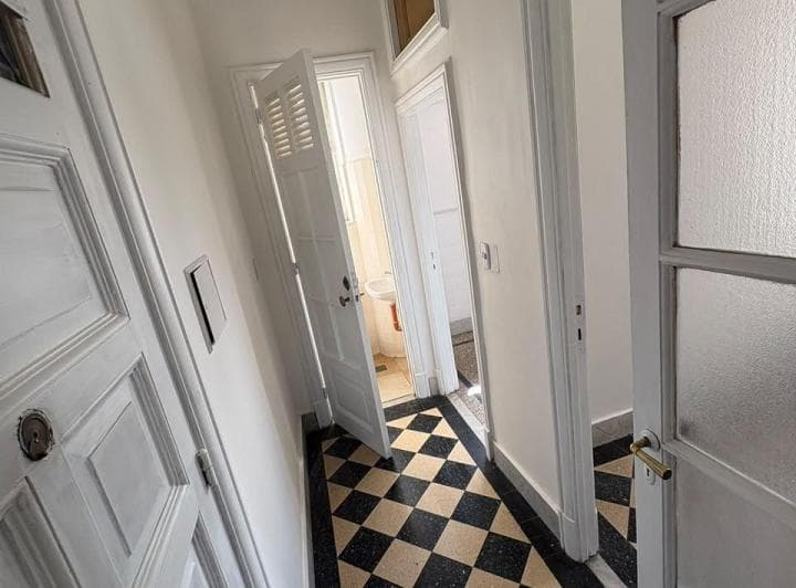 Pasillo con piso de baldosas de cuadros blancos y negros, acceso a otros cuartos.