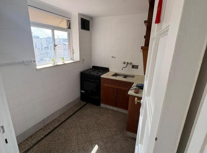 Cocina con mesada, bacha, anafe y alacenas de madera, ventana.