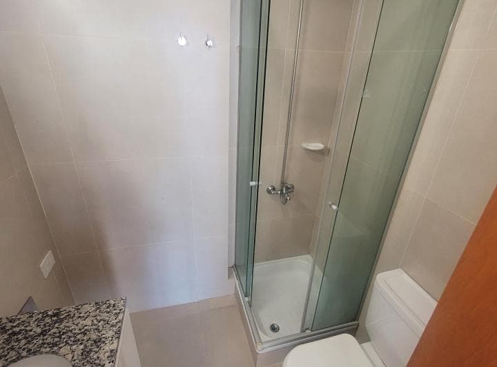Baño completo con ducha con mampara, inodoro y vanitory.