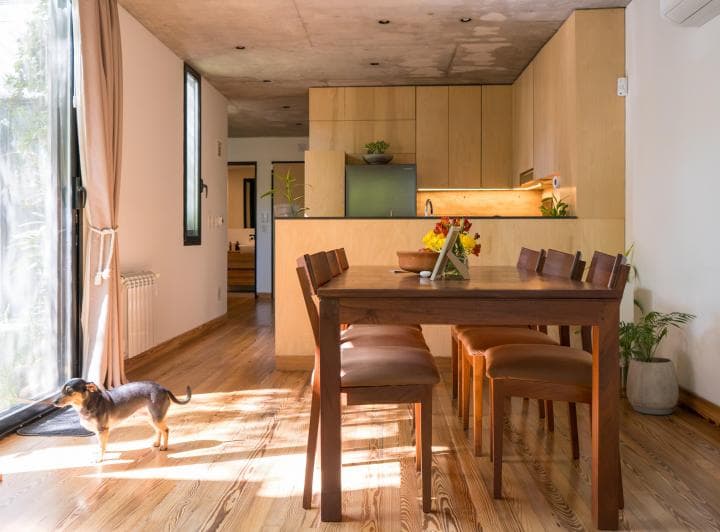 Living comedor con mesa de madera, cocina integrada y salida al exterior.