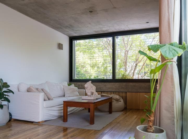 Living con sillón blanco, mesa ratona y gran ventana al exterior.