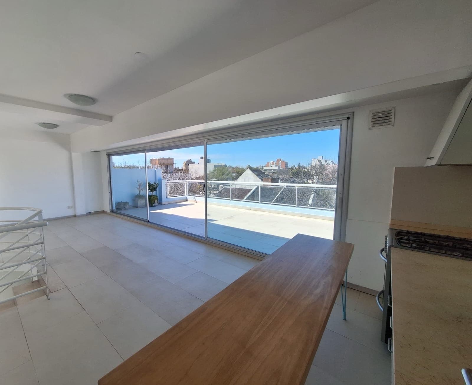Living con barra de madera y acceso a balcón terraza.