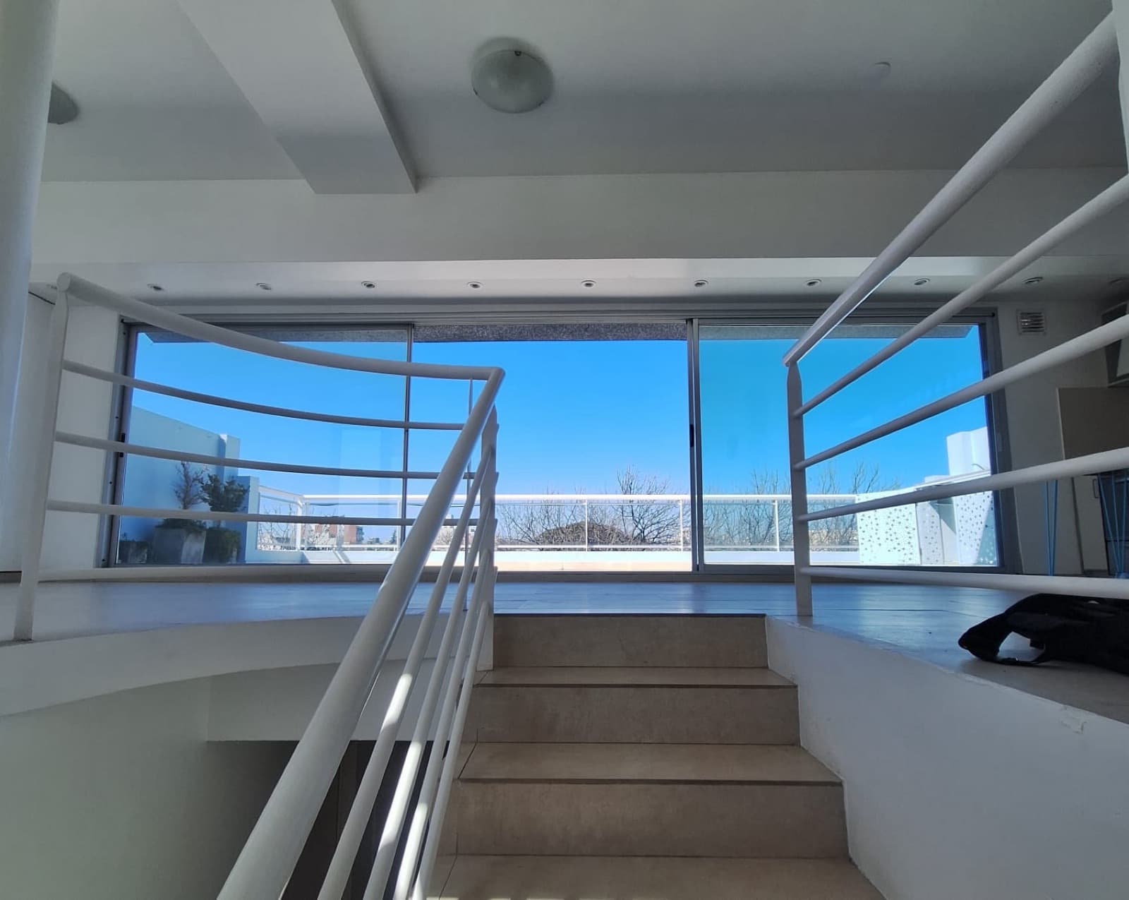Escalera que desciende a planta inferior, con amplios ventanales.