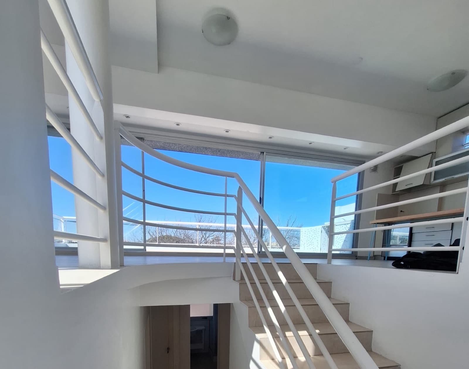 Escalera moderna en espacio abierto con ventanales.