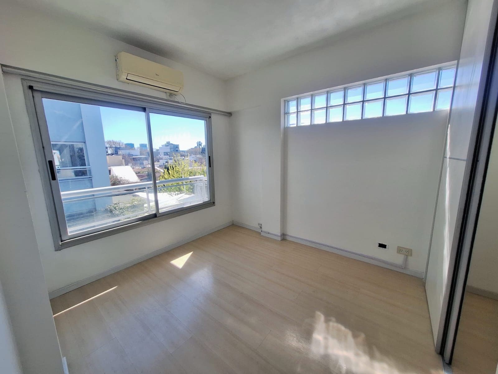 Dormitorio luminoso con gran ventana y aire acondicionado.