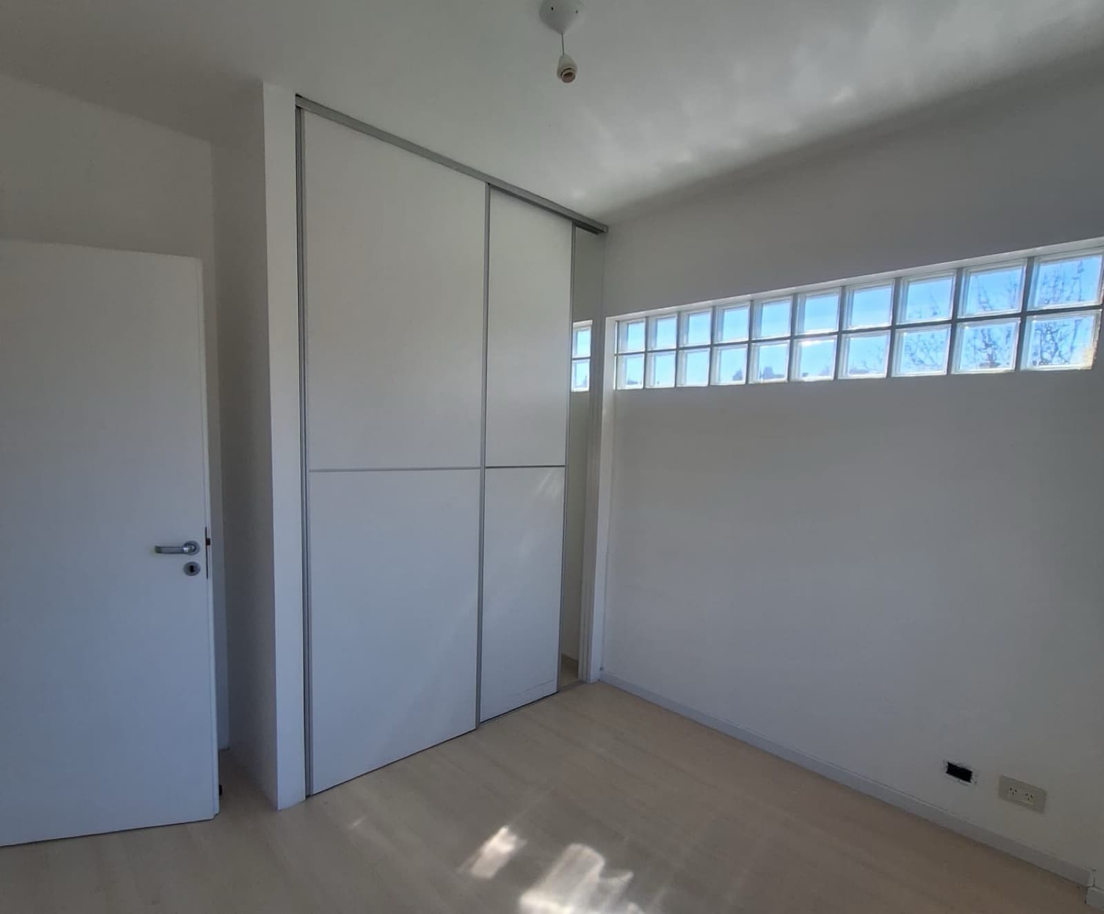 Dormitorio con placard de puertas corredizas y bloques de vidrio.
