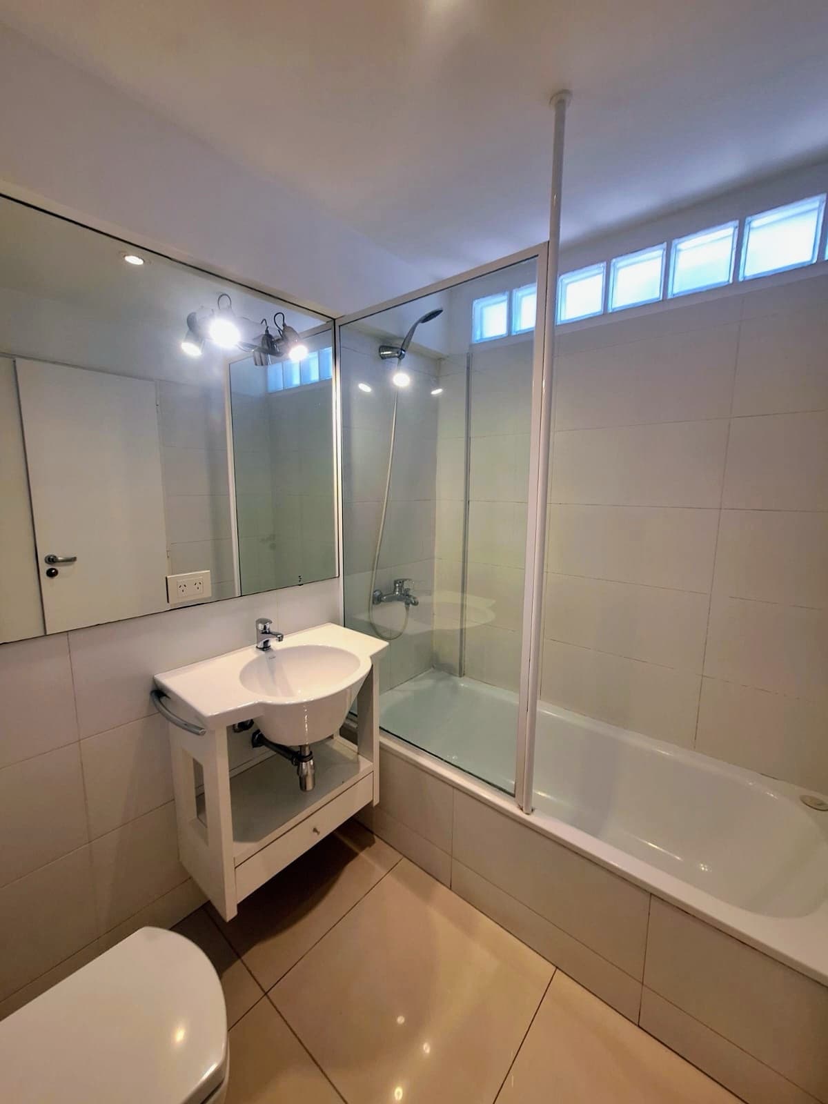 Baño con bañera y ducha, bacha, inodoro y espejo.