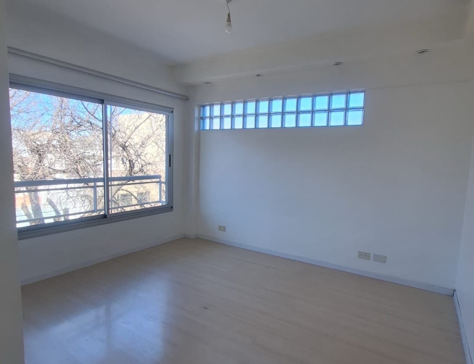 Dormitorio vacío con ventana y bloques de vidrio decorativos.