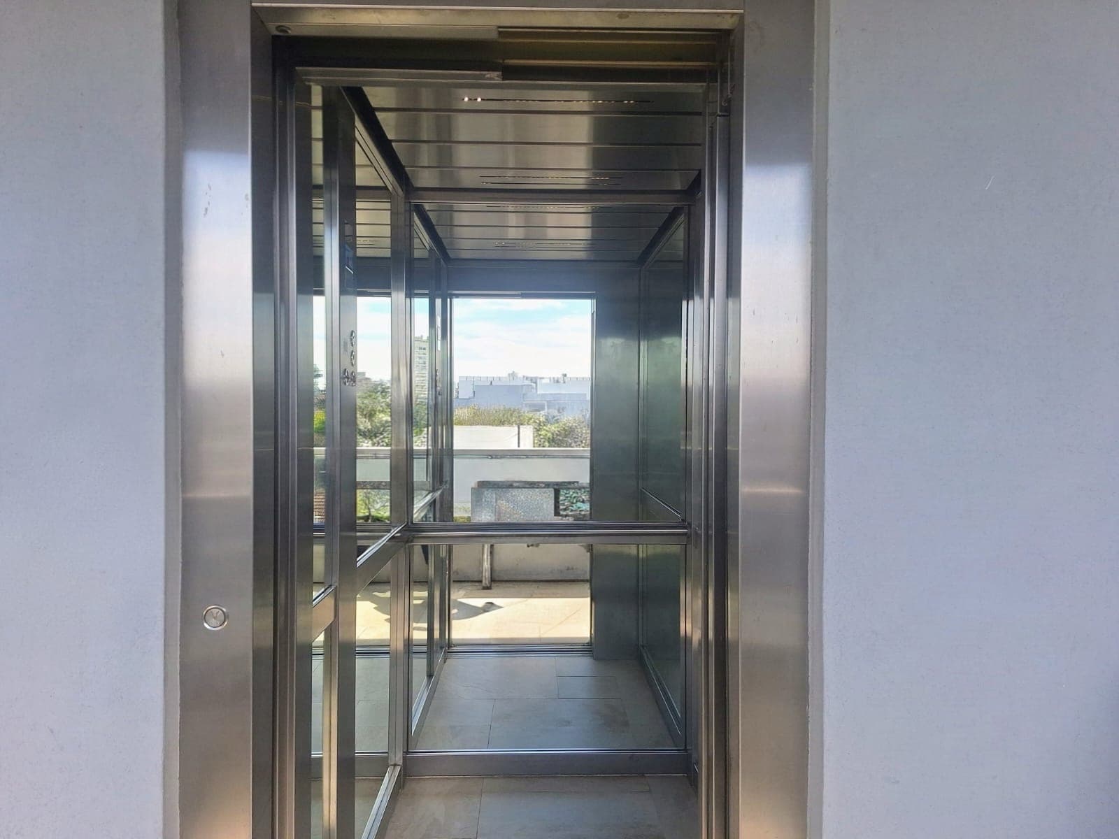 Ascensor de vidrio con vista a los pasillos y exterior.