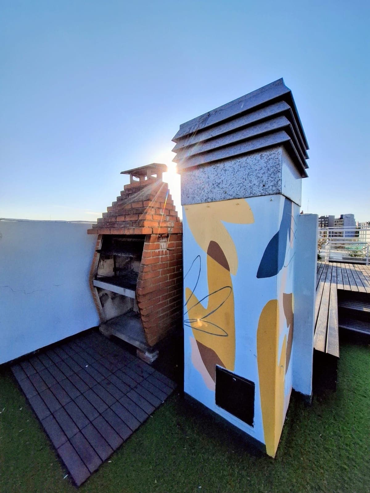 Terraza con parrilla de ladrillos y chimenea con diseño moderno.