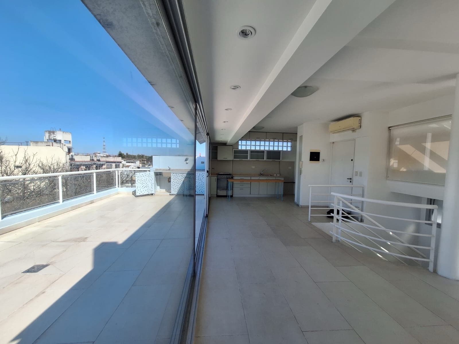 Living-comedor integrado con grandes ventanales y acceso a balcón terraza.