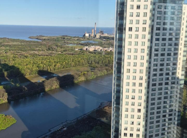 Vista panorámica al río, áreas verdes y edificios altos desde una ventana.