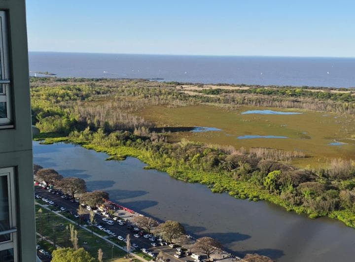 Vista aérea de paisaje con río, vegetación y una avenida con autos.