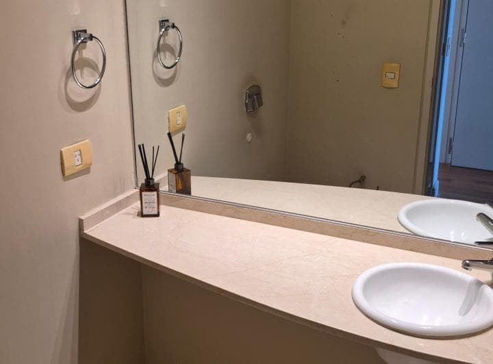 Toilette con vanitory, bacha blanca y espejo grande en la pared.