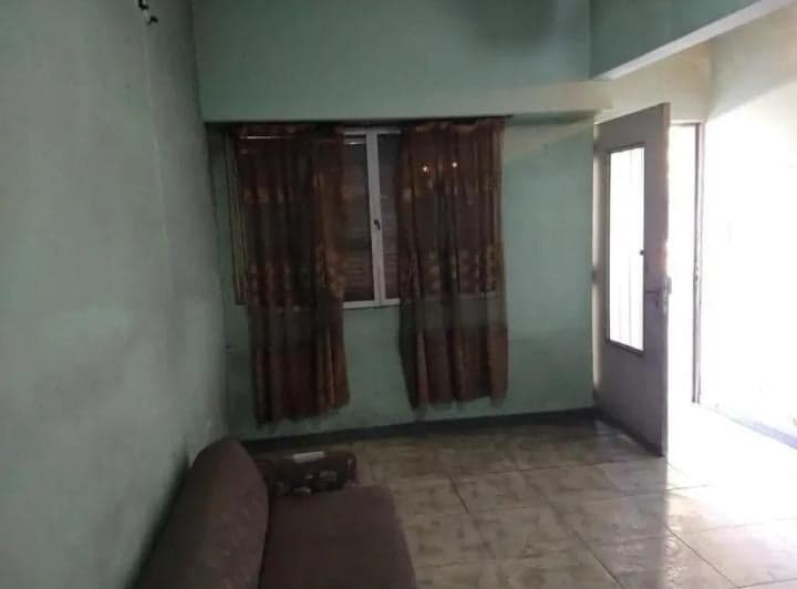 Living con un sofá, ventana con cortinas y puerta abierta.