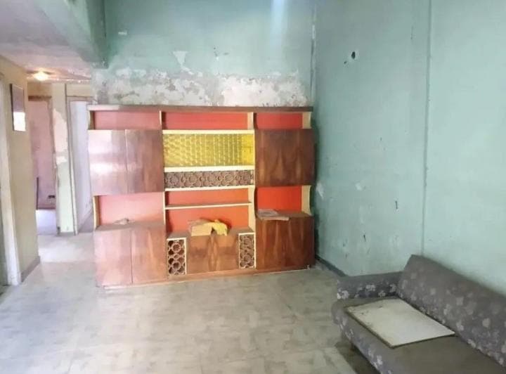 Living con mueble modular de madera y sofá viejo.