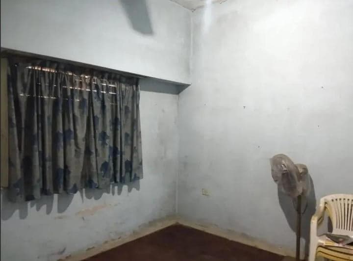 Dormitorio con ventana, ventilador de pie y paredes celestes.