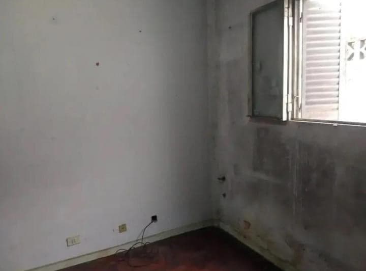 Dormitorio con ventana de celosías y paredes sin pintar.