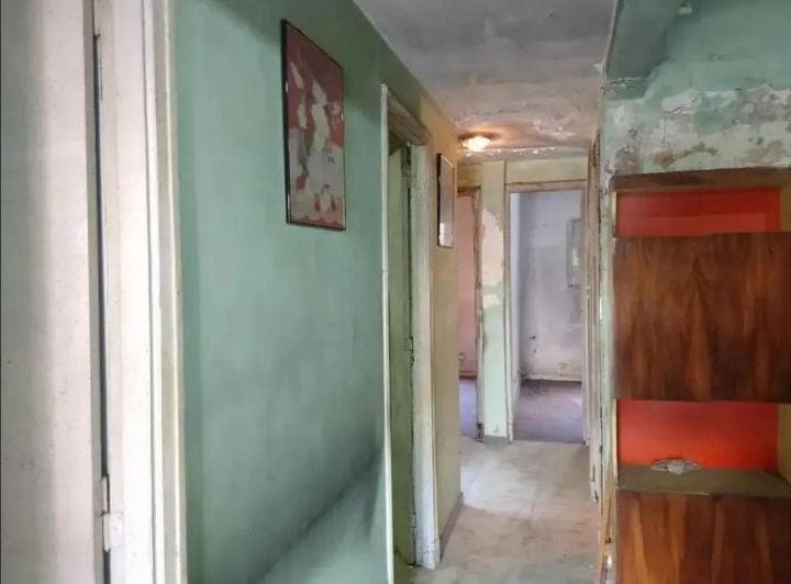 Pasillo largo con puertas a diferentes habitaciones y estante.
