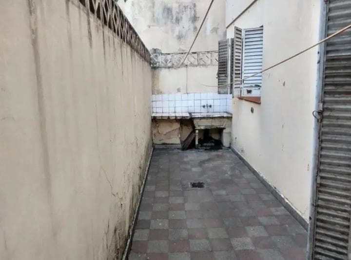 Patio exterior angosto con bacha de lavadero y paredes altas.