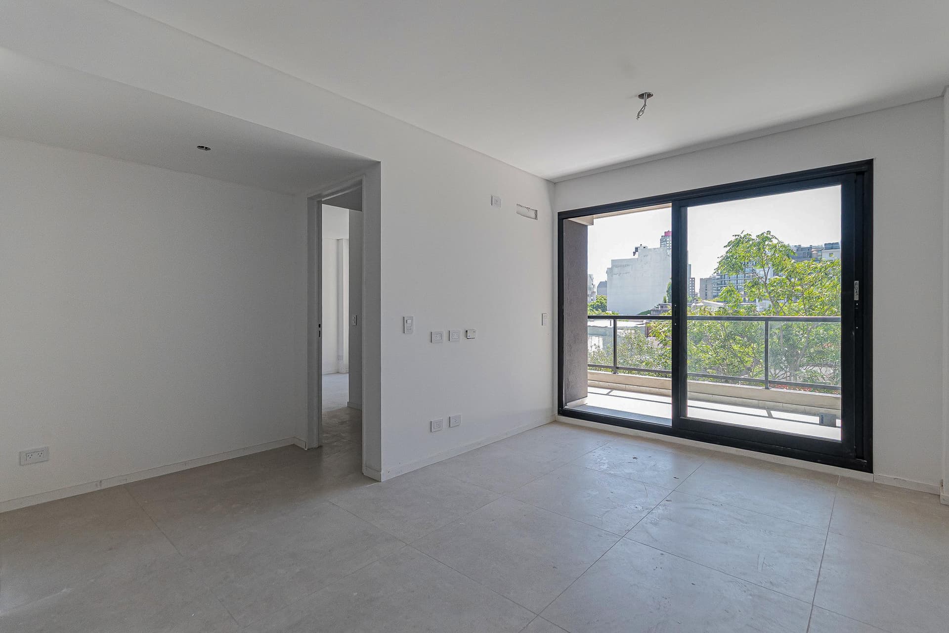 Dormitorio vacío con ventana al balcón y puerta de salida.
