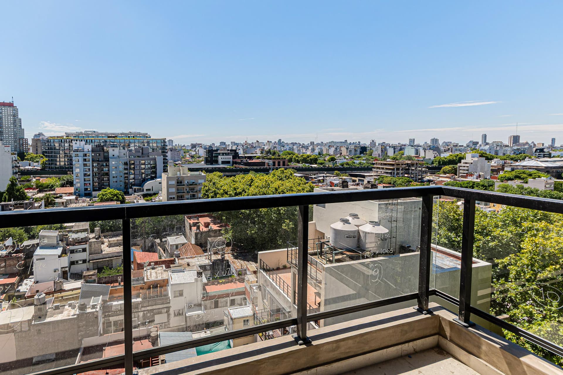 Vista panorámica de la ciudad desde un balcón con edificios y cielo azul.